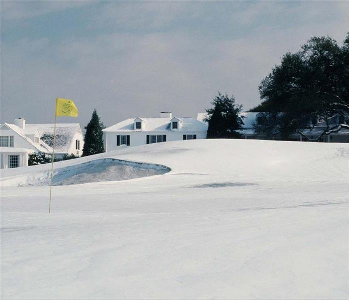 Snow covered golf course image from the Augusta National Golf Club The Master's with yellow flag sticking out of snow