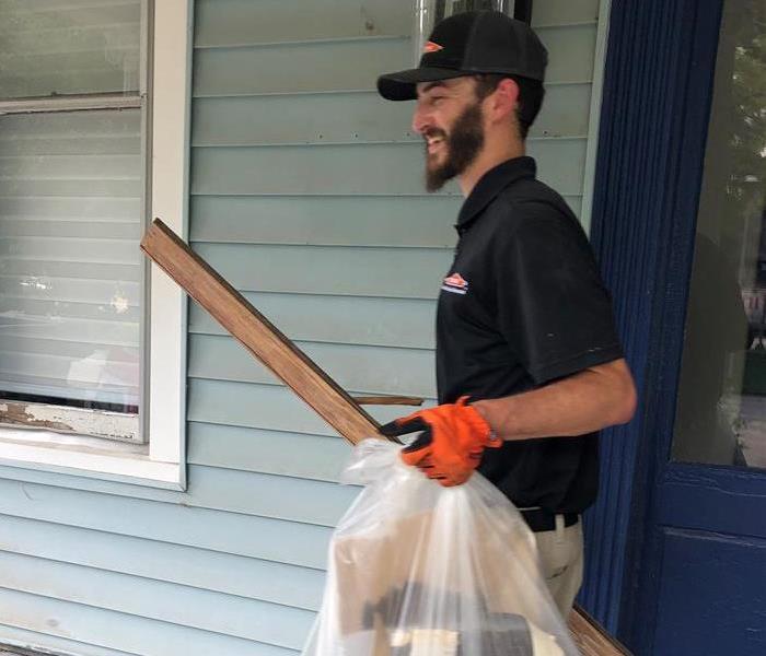 Servpro crew member in black shirt removes debris from an apartment complex