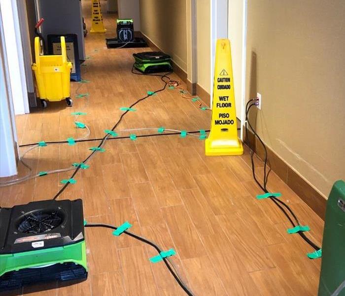 Air movers in hallways with green tape holding down cords to the floor.