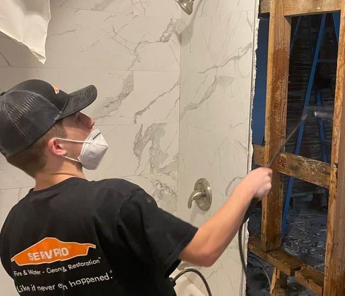 SERVPRO crew member in black shirt sprays antimicrobial to help prevent potential mold growth