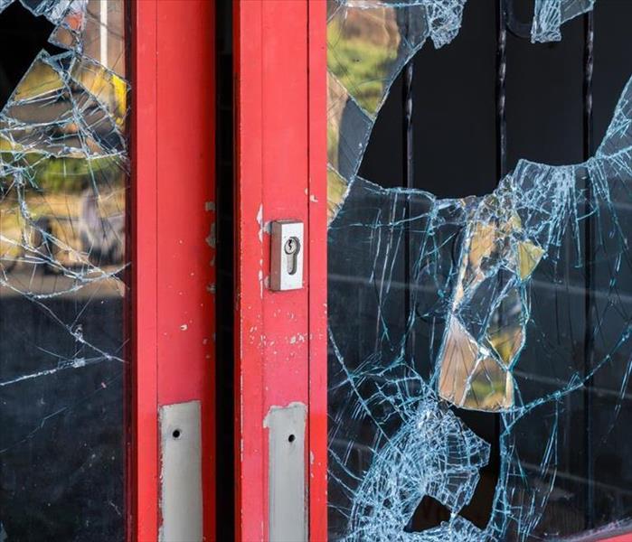 A broken window of a door from vandals breaking into a building.